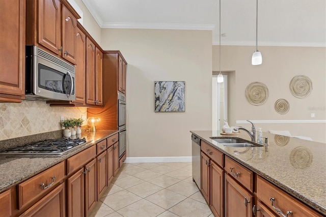 kitchen featuring stone countertops, stainless steel appliances, a sink, brown cabinetry, and pendant lighting