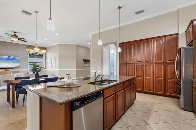 kitchen featuring decorative light fixtures, appliances with stainless steel finishes, open floor plan, a sink, and an island with sink