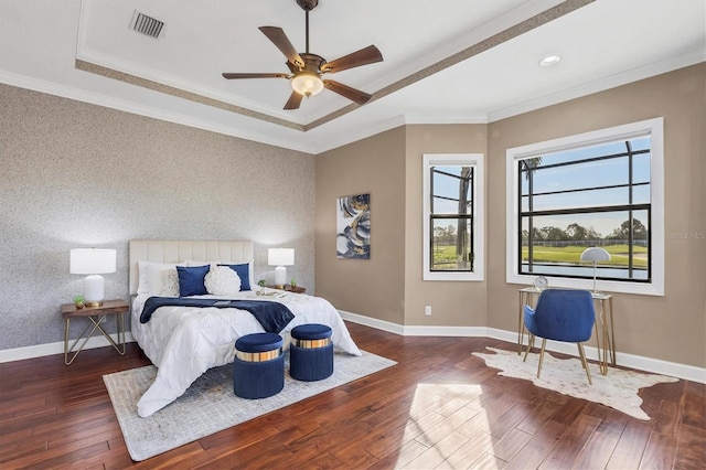 bedroom with dark wood-style floors, an accent wall, baseboards, and a tray ceiling