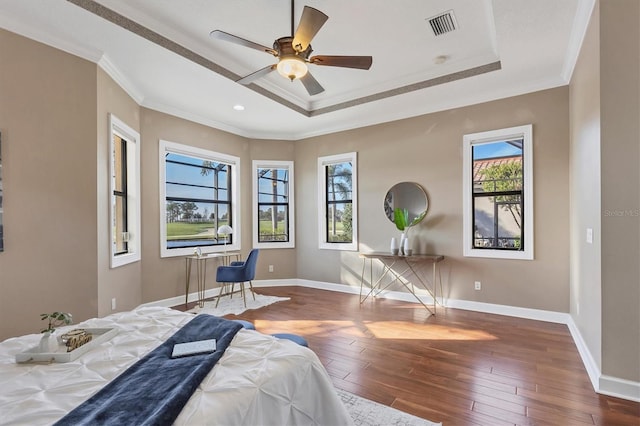 bedroom with a tray ceiling, crown molding, visible vents, and dark wood-style flooring