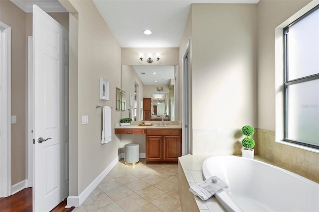 bathroom featuring tile patterned flooring, vanity, baseboards, and a bath