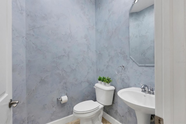 bathroom featuring baseboards, a sink, and toilet