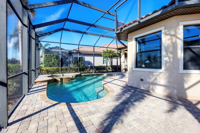 view of pool featuring glass enclosure, a patio, and a pool with connected hot tub