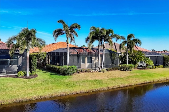 back of house featuring a water view, glass enclosure, and a lawn