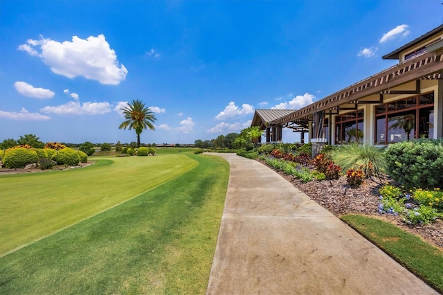 view of community featuring view of golf course and a lawn