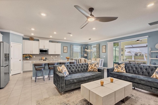 living room featuring a ceiling fan, visible vents, crown molding, and light tile patterned flooring