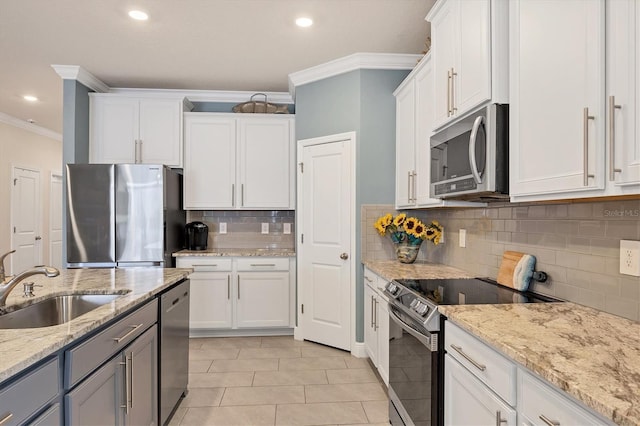 kitchen featuring white cabinets, light stone counters, stainless steel appliances, crown molding, and a sink