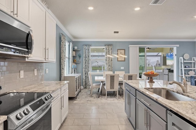 kitchen featuring stainless steel appliances, a sink, light stone countertops, and white cabinets