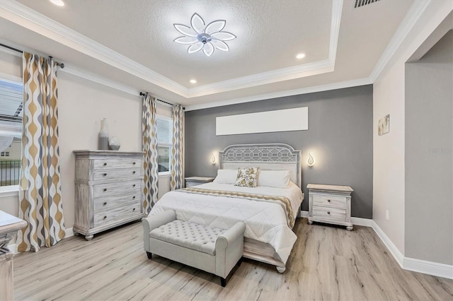 bedroom with baseboards, a raised ceiling, light wood-style flooring, ornamental molding, and a textured ceiling