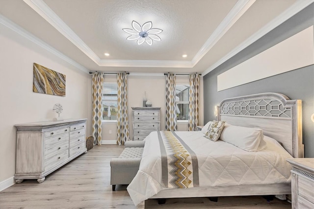 bedroom with ornamental molding, a tray ceiling, light wood-type flooring, and baseboards