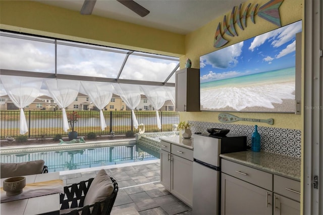 view of swimming pool featuring an outdoor kitchen, a lanai, a water view, a fenced in pool, and a patio area