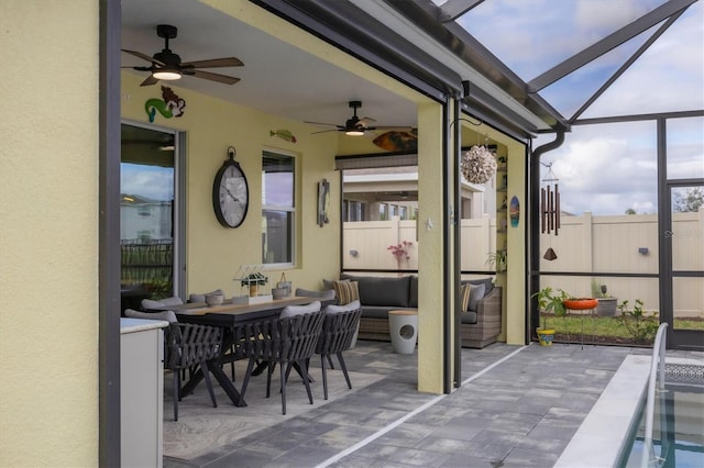 view of patio / terrace featuring a lanai, fence, an outdoor living space, and a ceiling fan