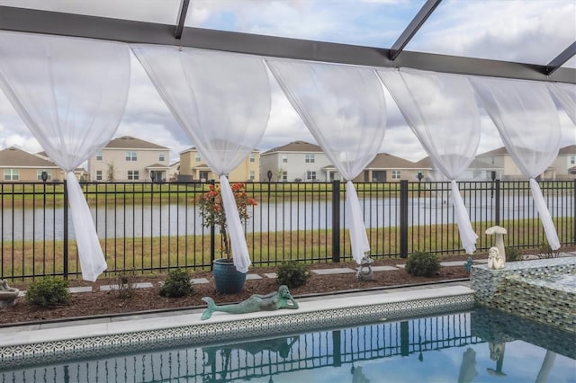 view of swimming pool with a water view, fence, and a residential view