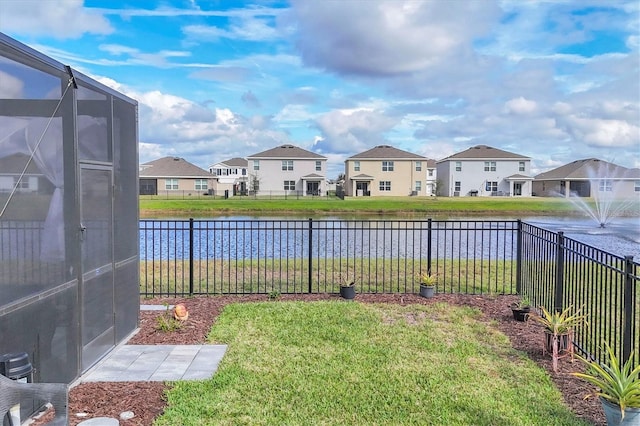 view of yard featuring glass enclosure, a water view, a fenced backyard, and a residential view