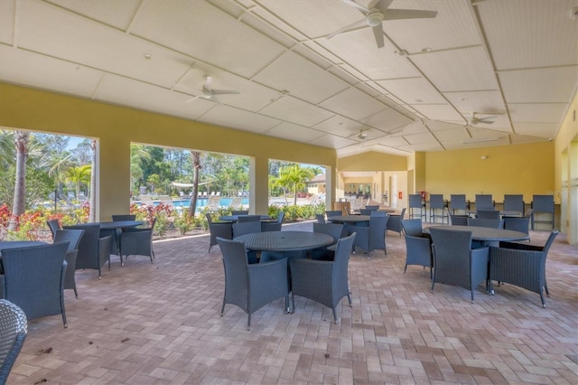 exterior space featuring outdoor dining space, a ceiling fan, and an outdoor pool