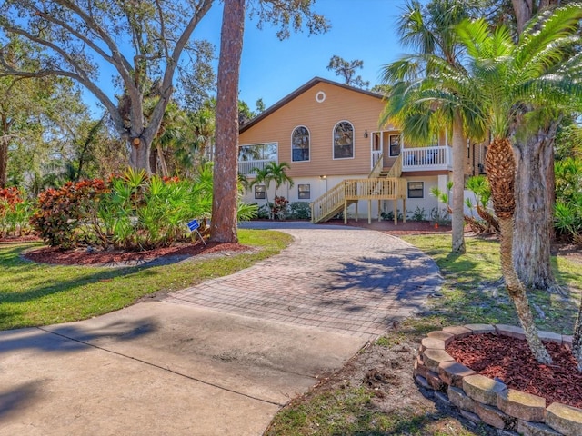 view of front of property with stairs, decorative driveway, and a front yard