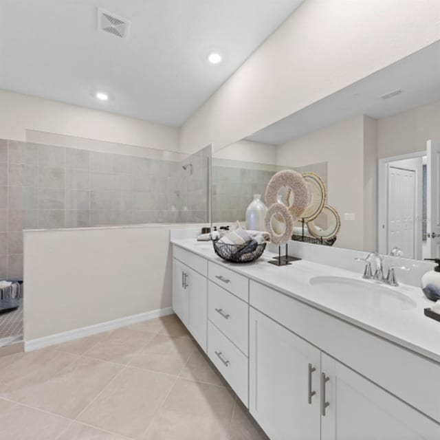 full bath featuring double vanity, visible vents, a sink, tile patterned flooring, and walk in shower