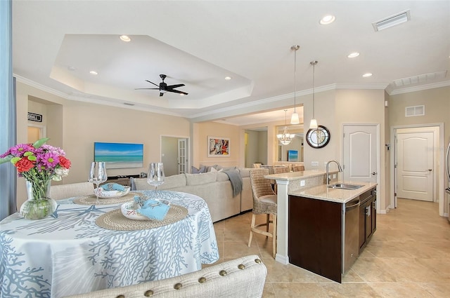 kitchen with visible vents, open floor plan, decorative light fixtures, dark brown cabinets, and a sink