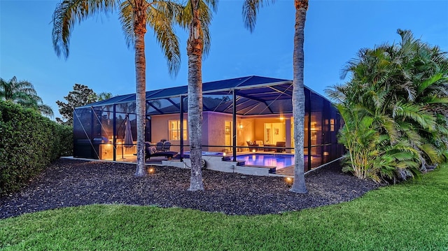 back of property at dusk featuring a lanai, a patio area, and an outdoor pool