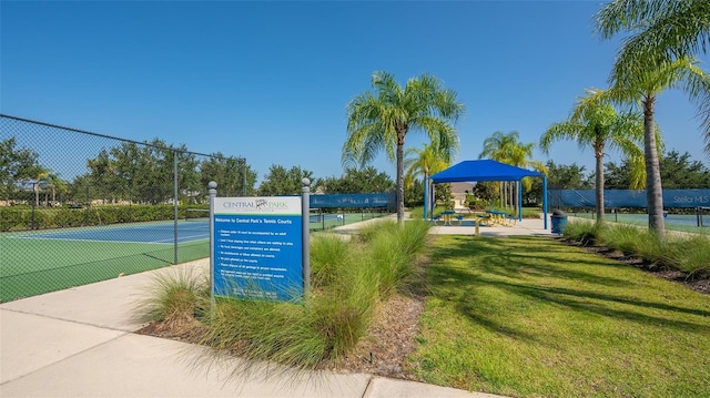 view of home's community featuring a tennis court, fence, a lawn, and a gazebo