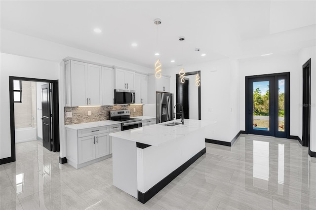 kitchen featuring light stone counters, stainless steel appliances, hanging light fixtures, a kitchen island with sink, and white cabinetry