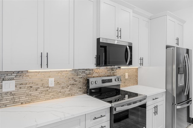 kitchen featuring appliances with stainless steel finishes, decorative backsplash, white cabinetry, and light stone countertops