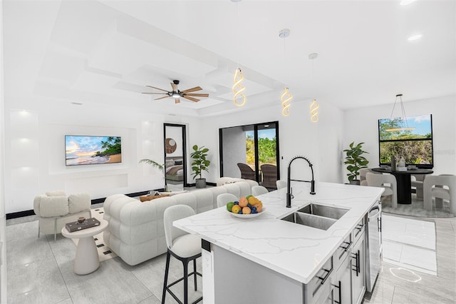 kitchen with hanging light fixtures, open floor plan, a sink, and an island with sink