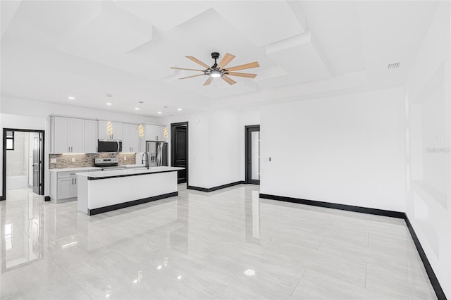 kitchen with a center island, light countertops, appliances with stainless steel finishes, white cabinets, and baseboards