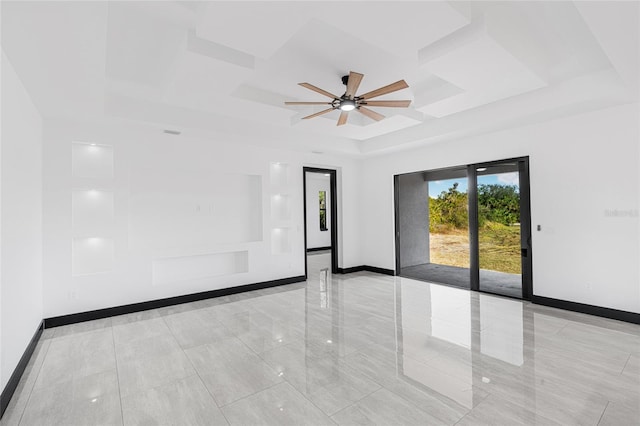 spare room with a tray ceiling, ceiling fan, and baseboards