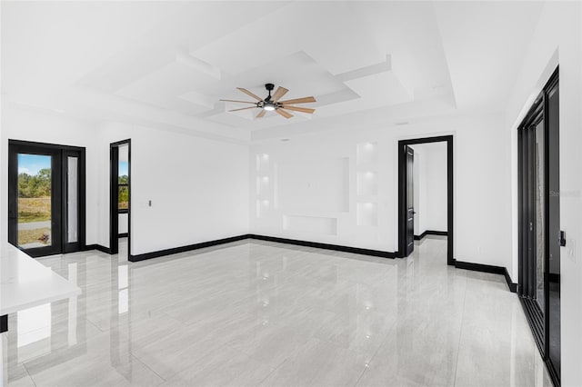 spare room featuring ceiling fan, marble finish floor, a raised ceiling, and baseboards