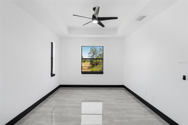 unfurnished room featuring a tray ceiling, visible vents, ceiling fan, and baseboards