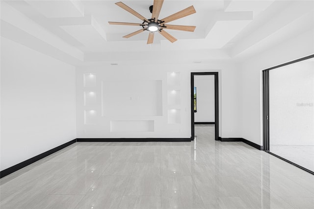 spare room featuring baseboards, a tray ceiling, and a ceiling fan