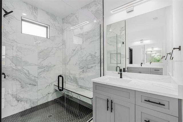 full bath with visible vents, a marble finish shower, and vanity