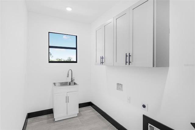 laundry area with cabinet space, a sink, electric dryer hookup, and baseboards