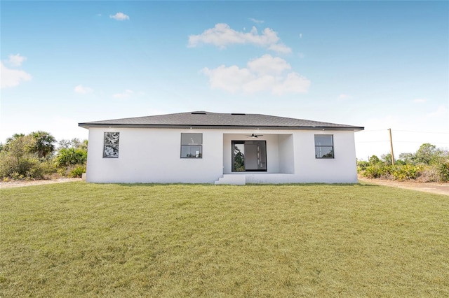 back of property with a yard, ceiling fan, and stucco siding