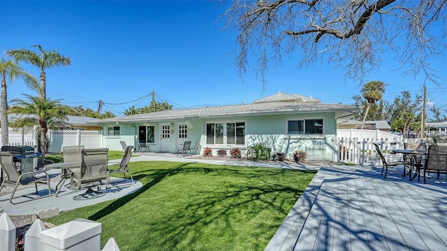 rear view of property with a yard, fence, and stucco siding