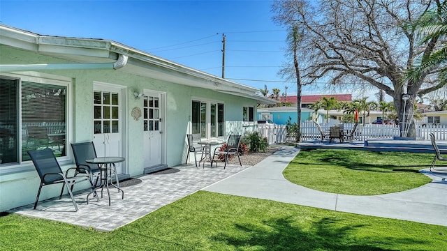 back of house featuring a yard, a patio area, fence, and stucco siding