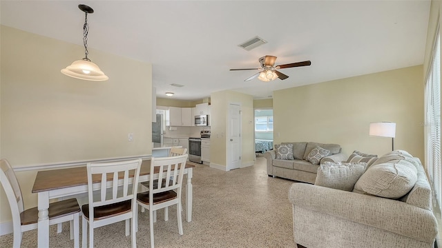 living room with light speckled floor, baseboards, visible vents, and a ceiling fan