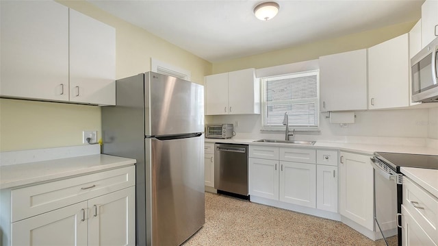 kitchen with appliances with stainless steel finishes, light countertops, white cabinets, and a sink