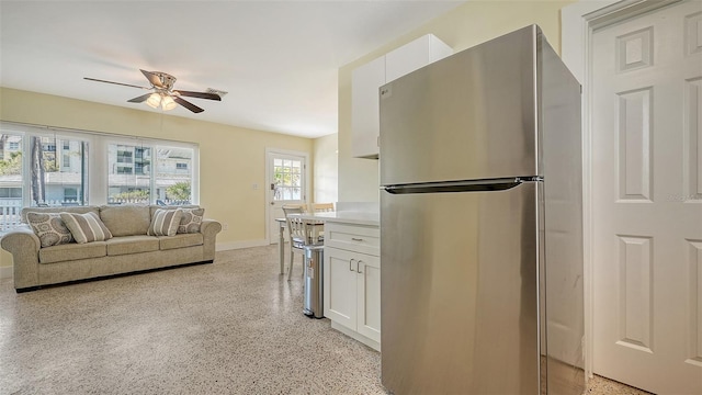 kitchen with white cabinets, a ceiling fan, freestanding refrigerator, light countertops, and light speckled floor