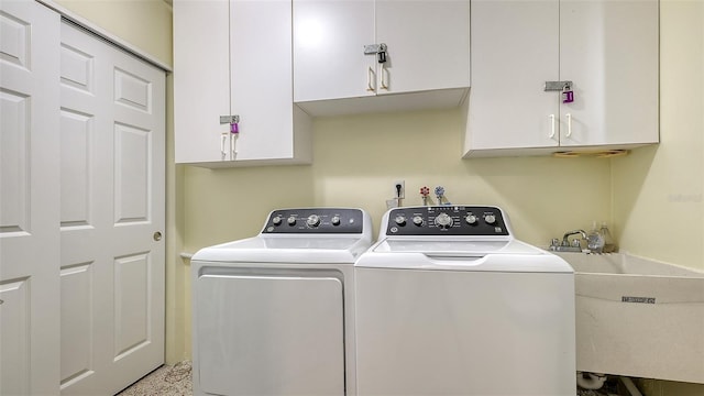 laundry area with cabinet space, separate washer and dryer, and a sink