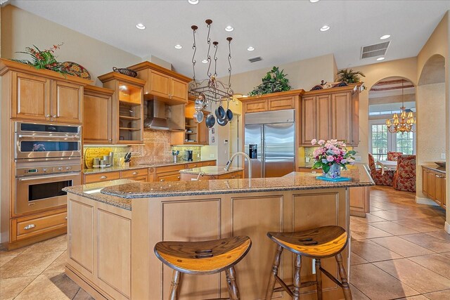 kitchen with glass insert cabinets, a kitchen island with sink, visible vents, and stainless steel appliances