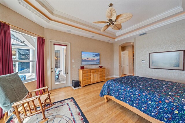 bedroom featuring a tray ceiling, arched walkways, visible vents, ornamental molding, and wood finished floors