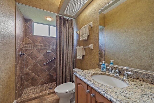 full bath featuring a textured wall, toilet, tile patterned flooring, vanity, and a shower stall