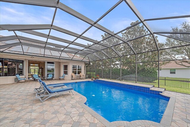 outdoor pool featuring glass enclosure, a patio area, and fence