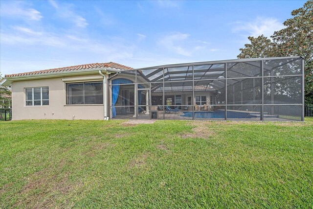 rear view of property featuring a yard, stucco siding, glass enclosure, an outdoor pool, and a tiled roof