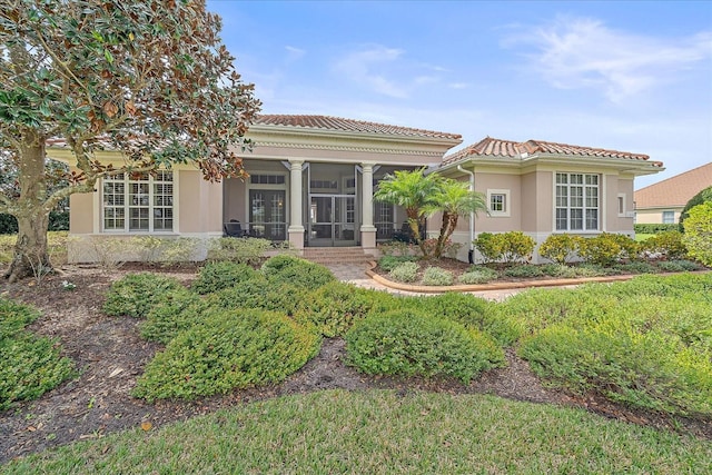 view of front of property featuring a sunroom, a tiled roof, and stucco siding