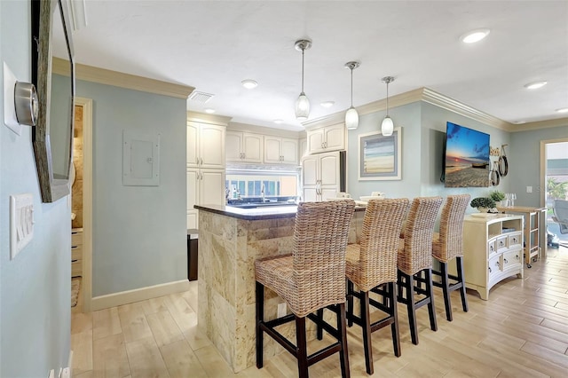 kitchen with visible vents, hanging light fixtures, light wood finished floors, and paneled built in refrigerator
