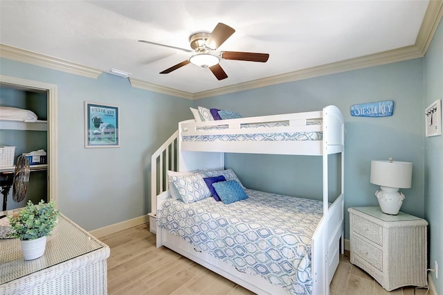 bedroom featuring ornamental molding, light wood-type flooring, a ceiling fan, and baseboards