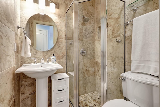 bathroom with a stall shower, toilet, and tile walls